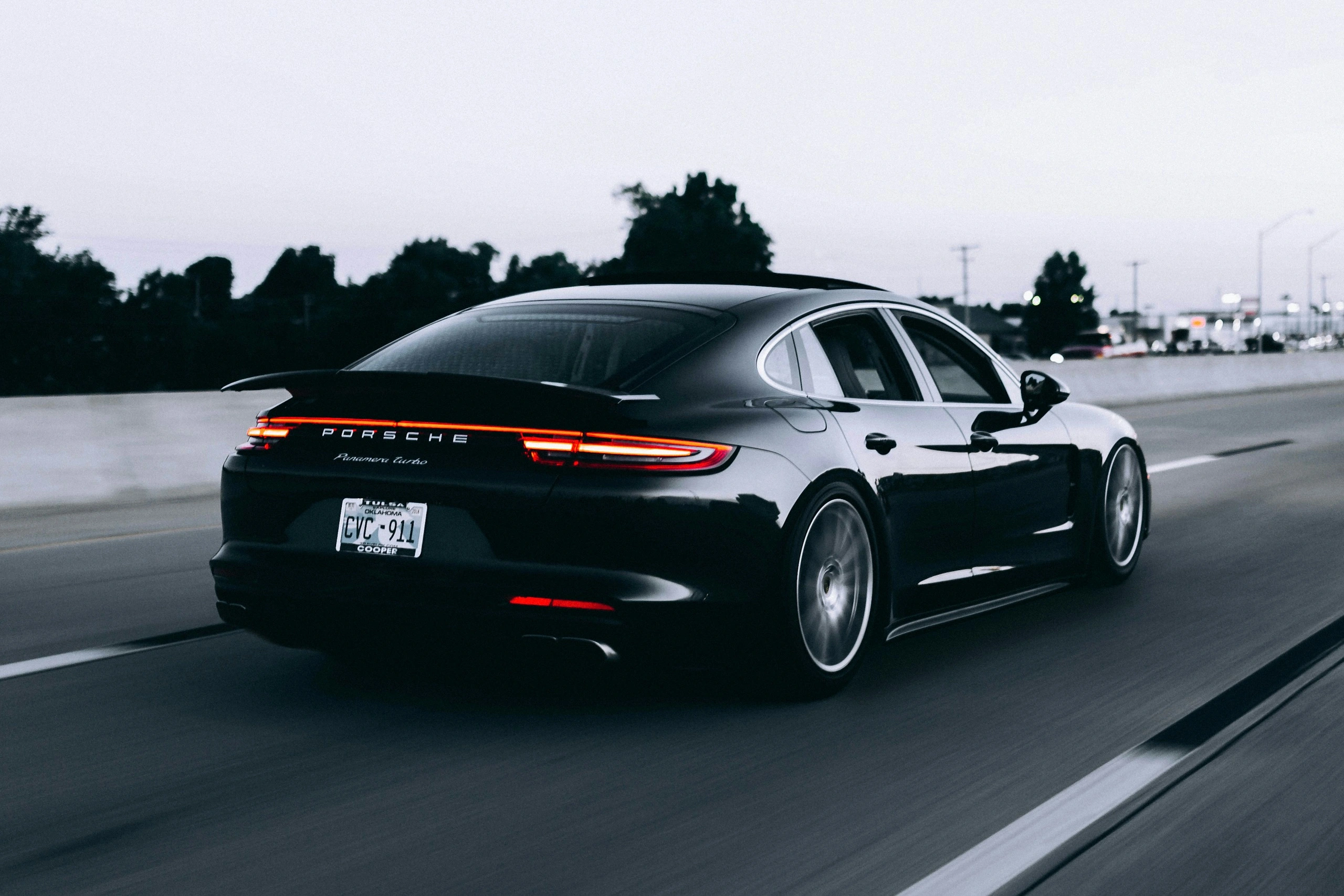 Une Porsche noire photographiée de trois quarts arrière sur une route, pour cette exploration automobile.