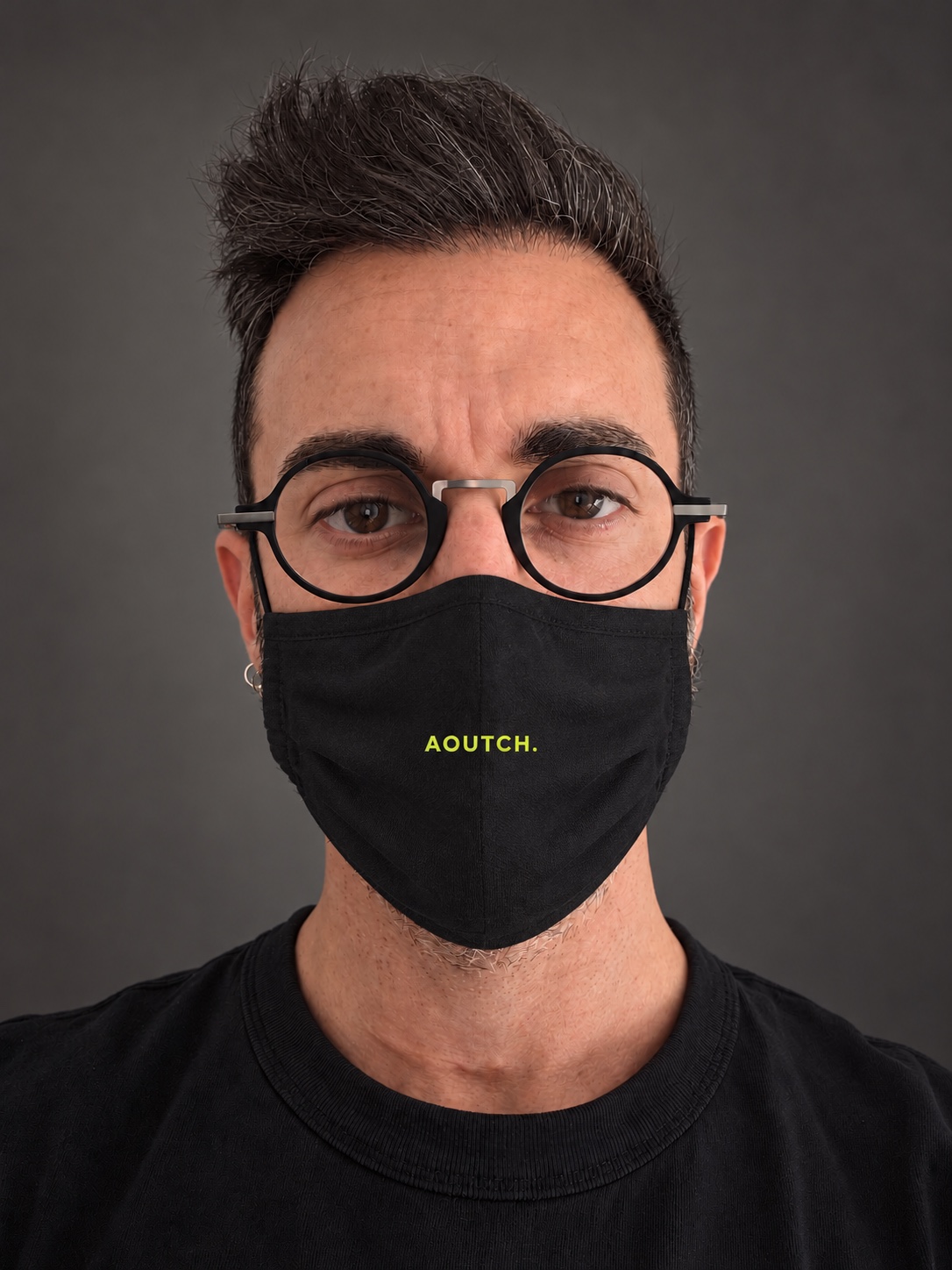 Portrait de Roberto portant un masque noir AOUTCH, sur un fond gris sobre.